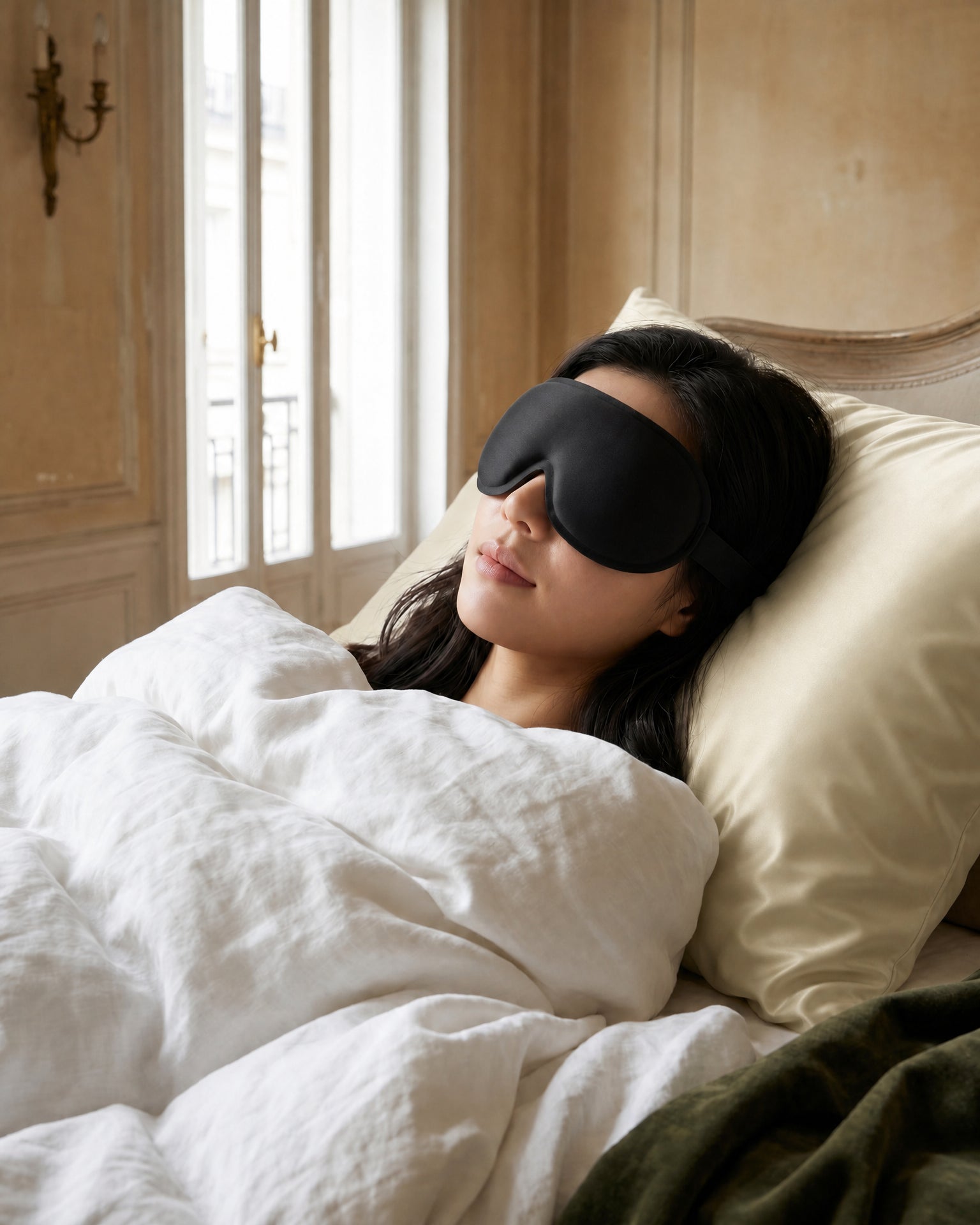 Somnia Sable 3D contour blackout sleep mask resting on neutral bedding in a serene bedroom